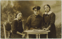 CARTE-PHOTO MONTRANT UN JEUNE SOLDAT ALLEMAND POSANT AVEC DEUX JEUNES FILLES (SOEURS ?)