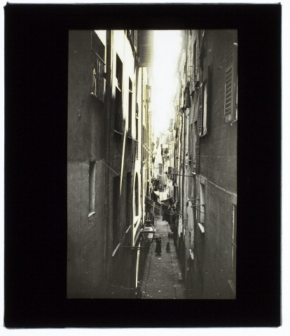 [Une rue étroite des vieux quartiers de Nice. Cordes à linge tendues entre les maisons]