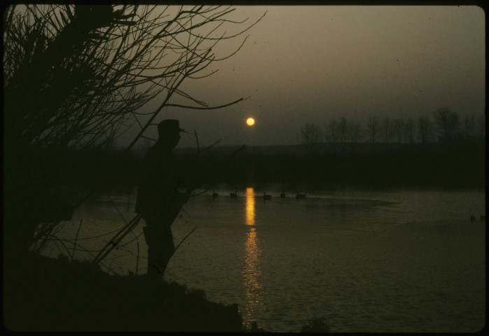[Un chasseur regardant le coucher du soleil sur les marais]