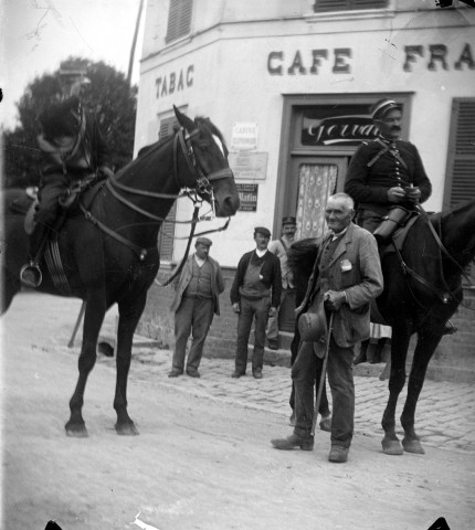 Deux gendarmes à cheval devant un café
