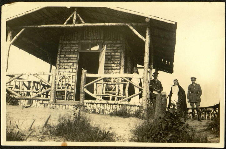 Infirmières de l'équipe de Madame Panas, de la Société de secours aux blessés et militaires, posant avec des officiers britanniques devant une cabane en rondins de bois