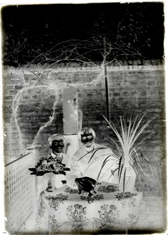 Un homme et un garçon assis dans un jardin. Au second plan, une pompe à eau