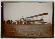 Photographie montrant de nombreux civils à côté d'un avion ZODIAC 2S au sol. Un phare maritime au second plan