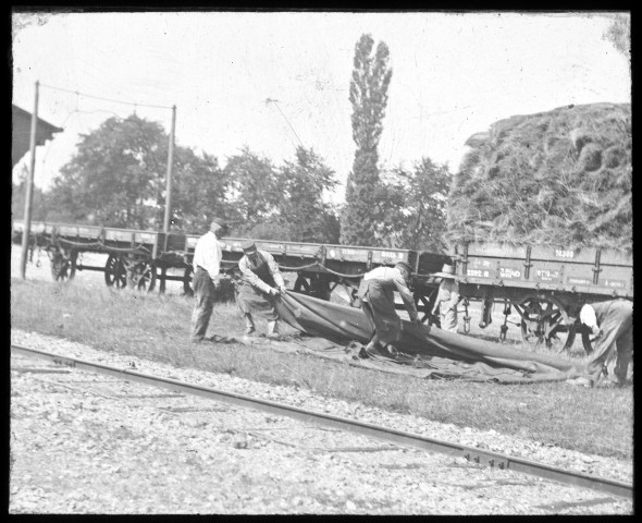 Les ouvriers de chemin de fer bâchant un train de marchandises