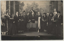 Amiens. Scène d'une pièce de théâtre. Seize acteurs posent devant un décor représentant un jardin. Lucien Pilette est au centre, une carafe à la main