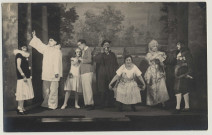 Amiens. Scène d'une pièce de théâtre. Huit acteurs posent devant un décor représentant un jardin arboré. Lucien Pilette se trouve au centre et porte un chapeau