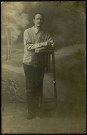 Portrait studio en pied de Louis Rousselle lors de sa captivité en Allemagne. La manche droite de sa veste de prisonnier est marquée de la lettre K pour Kommando (unité de travail forcé)