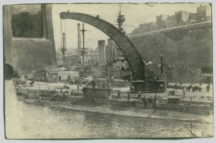 THE SUBMARINE E.2 AT MALTA. THE BATTLESHIP "CORNWALL" IS IN THE BACKGROUND E.2 DISTINGUISED ITSELF IN THE DARDANELLES
