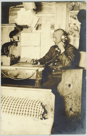PHOTOGRAPHIE MONTRANT UN SOLDAT ALLEMAND ASSIS A UNE TABLE ET TENANT UN RECEPTEUR TELEPHONIQUE. ECRITE EN ALLEMAND ET DATEE DU 22 NOVEMBRE 1917
