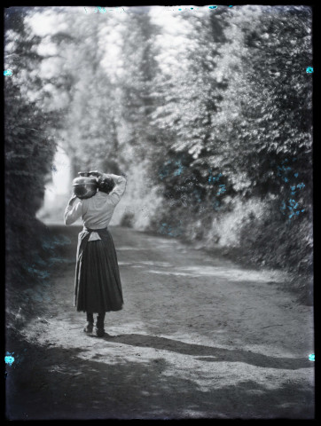 Scène rurale. Une femme portrait un brau d'eau sur son épaule