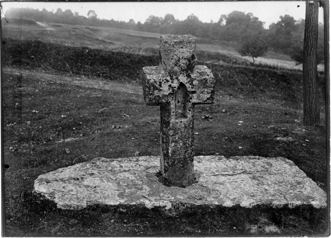 Une petite croix de grès érigée, sur un support de pierre