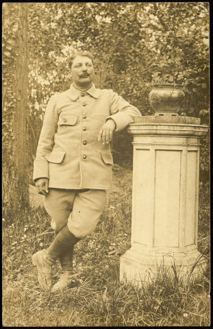 Carte photo représentant un soldat prénomé Ovide, près d'une colonne dans un jardin