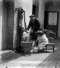 Scène domestique. Un vieil homme et une petite fille tirant de l'eau à la pompe
