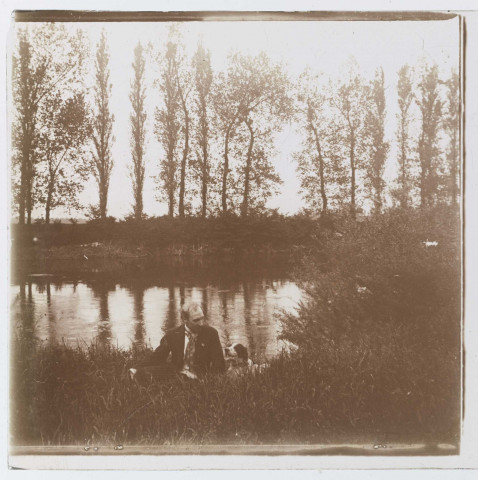 Homme assis avec son chien au bord d'une rivière