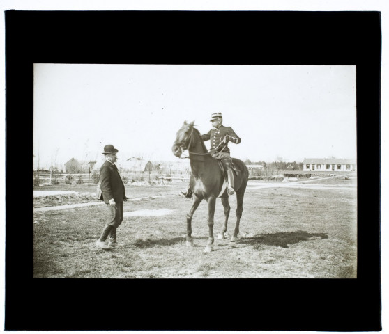 [Camp de Sissonne : rencontre d'un photographe de la Société photographique de Picardie et d'un officier à cheval. Au second plan, les baraquements militaires]