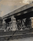 Ouvriers du chemin de fer travaillant sur les piliers d'un pont enjambant les voies de chemmin de fer