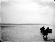 La plage à marée basse : une baigneuse, des pêcheurs tirant leur canot