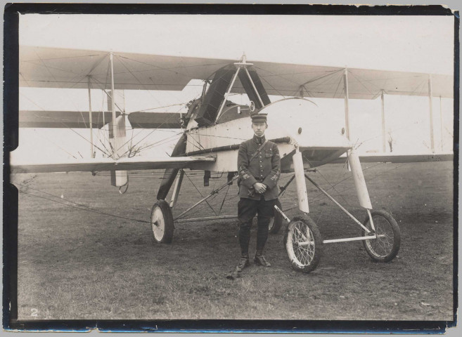 Photographie montrant un aviateur de face, les mains croisées sur le ventre, devant son avion VOISIN LA3