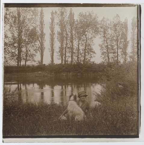Femme allongée avec son chien au bord d'une rivière