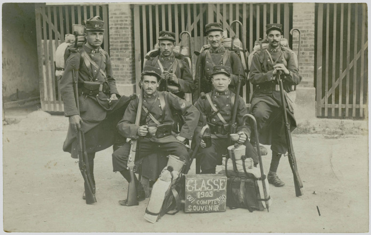 CARTE-PHOTO MONTRANT SIX SOLDATS DU 61EME REGIMENT D'INFANTERIE POSANT POUR LA PHOTOGRAPHIE. DEVANT EUX UN PANNONCEAU : "CLASSE 1905 QUI COMPTE 390 JOURS - SOUVENIRS". MATE