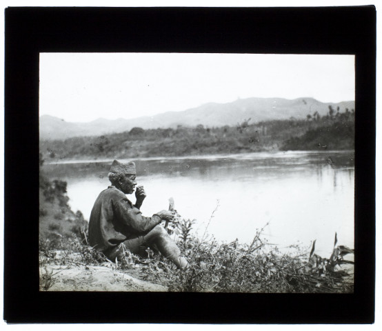 [Type d'homme malgache assis près d'un fleuve]