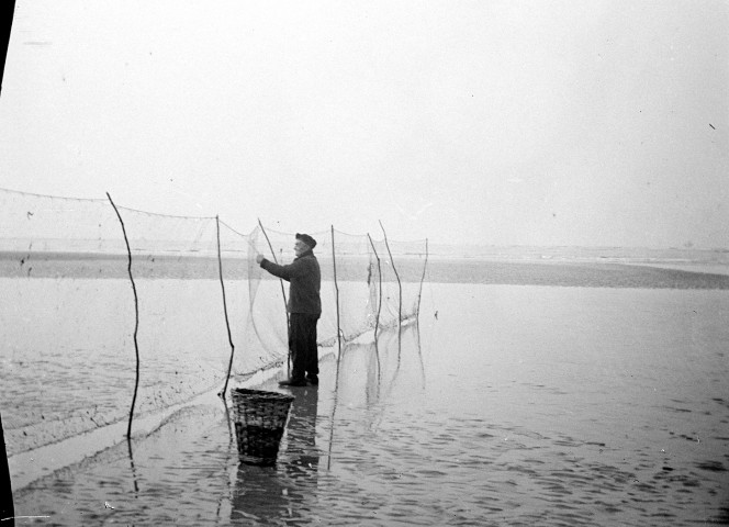 Paysage littoral. Un pêcheur posant ses filets sur la plage