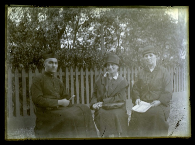 Un prêtre et deux femmes assis sur un banc