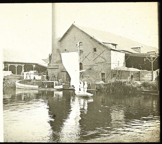 Petit bateau de plaisance sur un cours d'eau dans la Somme, près d'une usine