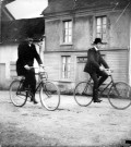 Scène rurale. Deux hommes traversant le village à vélo