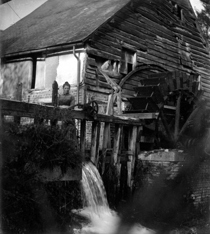 Une paysanne devant la chute d'un moulin à eau