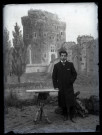 Portrait en pied d'un homme devant une tenture peinte représentant un château