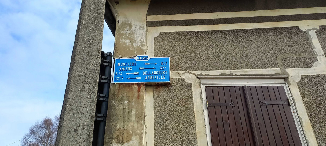 Ailly-le-Haut-Clocher. Ancienne plaque directionnelle dite plaque de cocher R.N. n° 35 vers Moufflers (5,2 km), Amiens (32 km), Bellancourt (6,4 km) et Abbeville (12,7 km)