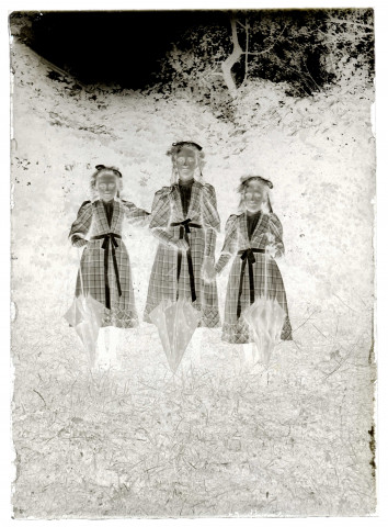 Scène de la vie quotidienne d'une famille bourgeoise. Trois jeunes filles en robes écossaisses dans un jardin