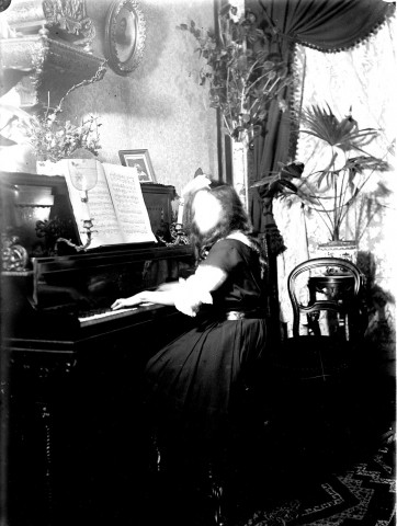 Scène de la vie quoditienne d'une famille bourgeoise. Portrait d'une jeune femme jouant du piano dans un salon du château de Long
