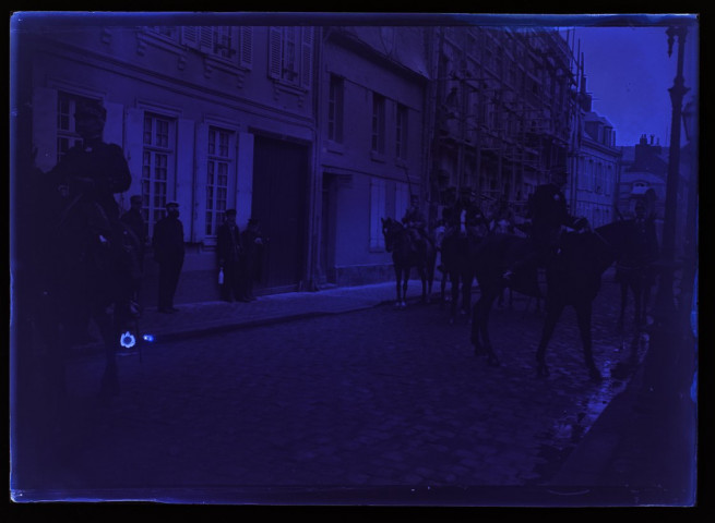 [Chasseurs à cheval dans une rue d'Amiens. Au second plan à gauche, on distingue un échafaudage sur la façade d'une maison]