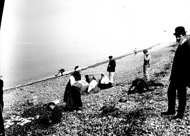 Paysage littoral. Un groupe de personnages sur la plage de galets