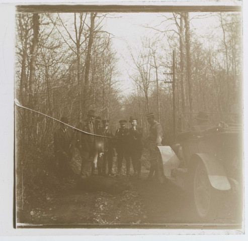 Chasseurs posant avec un sanglier à côté de la voiture en forêt