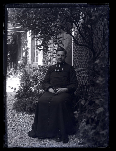 Portrait d'un prêtre assis dans un jardin