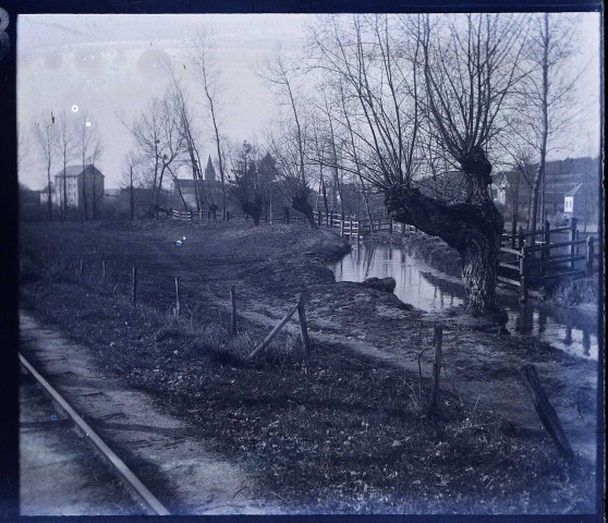 Environ du Crotoy (Somme). Un cours d'eau près d'une voie ferrée. Au second plan, le clocher d'une église
