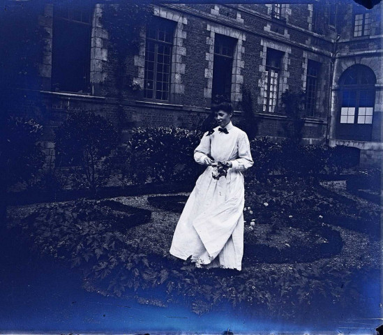 Amiens (Somme). Une jeune femme vêtue d'une robe blanche dans le jardin de la cour intérieure de l'Hospice Saint-Charles