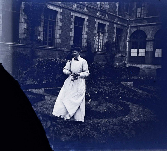 Amiens (Somme). Une jeune femme vêtue d'une robe blanche dans le jardin de la cour intérieure de l'Hospice Saint-Charles