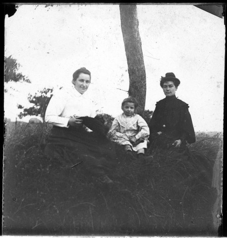 Portrait de deux femmes et un enfant assises sur un talus