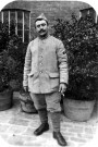 Arthur Lorge en uniforme une cigarette à la main posant devant des arbustes en pot