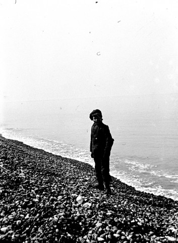 Paysage littoral. Portrait d'un jeune pêcheur sur la plage de galets