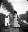 Portrait d'une jeune femme et une fillette se promenant sur un chemin arboré le long du canal