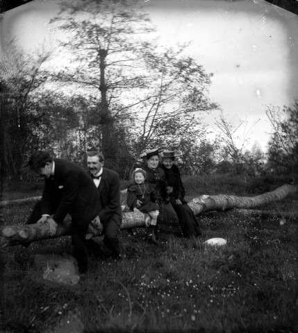 Portrait de famille posant sur un tronc d'arbre abattu