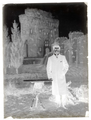 Portrait en pied d'un homme devant une tenture peinte représentant un château
