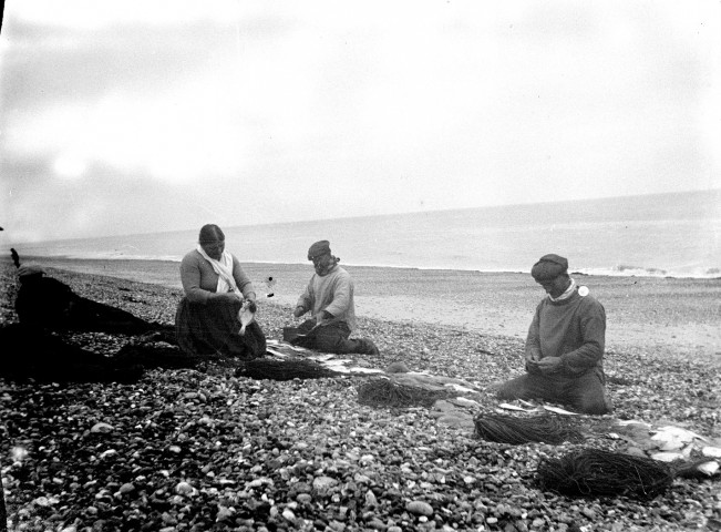 Paysage littoral.  Un groupe de pêcheurs préparant ses lignes sur la plage