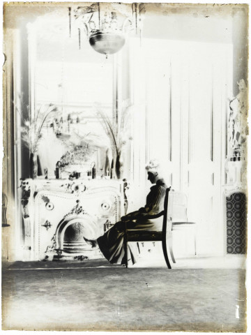 Environs de Lille (Nord). Intérieur d'une maison bourgeoise. Famille Danel. Portrait d'une femme assise devant une cheminée richement sculptée et ornée d'un grand miroir