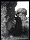 Portrait en pied d'un prêtre à côté d'énormes rochers